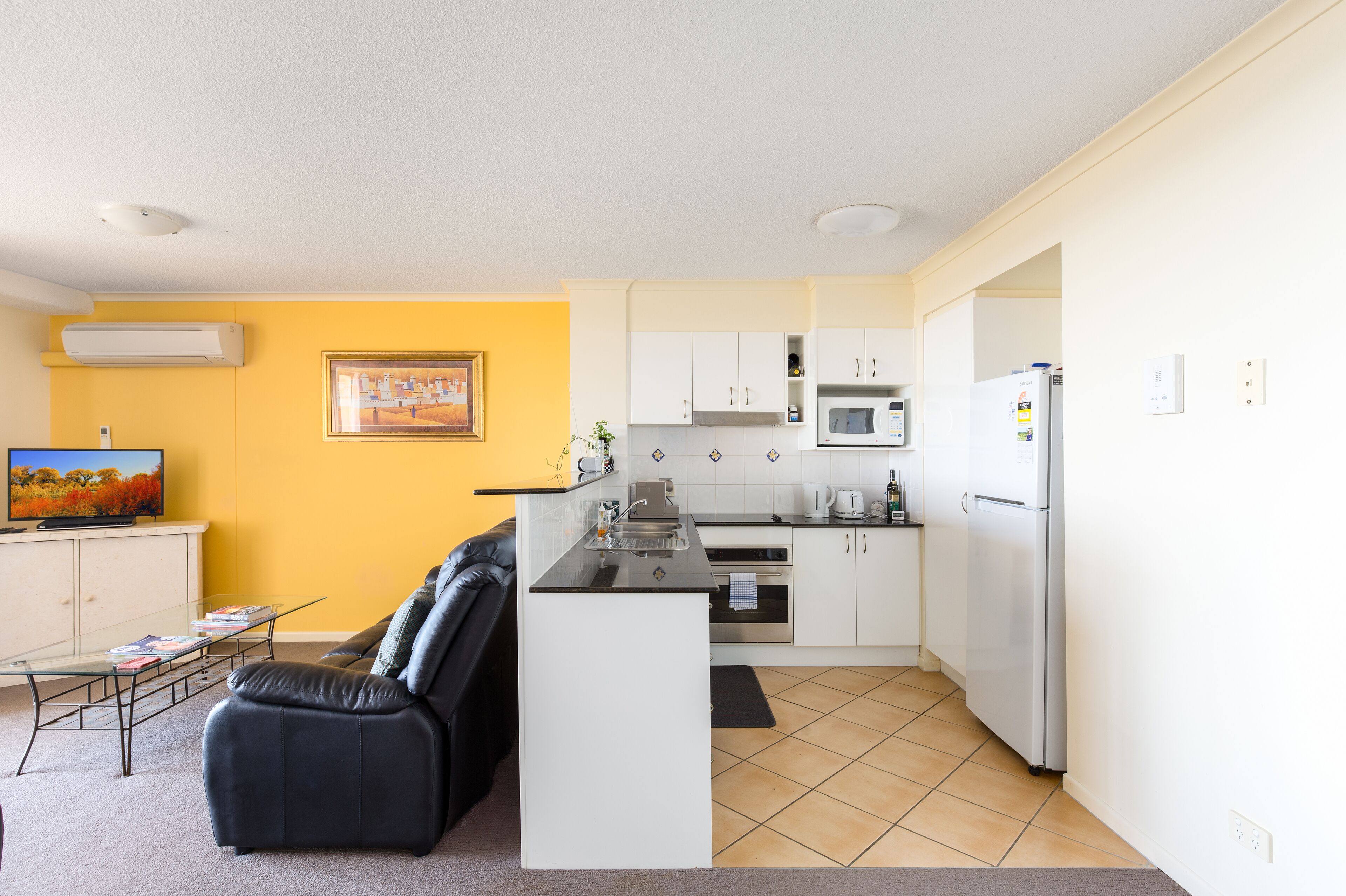 A compact living space with a kitchenette, a sofa, a coffee table, and a television.