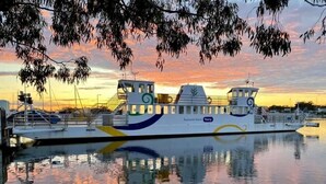 A ferry docked at a marina during sunset. - Captains Cove Waterfront Resort (Paynesville)