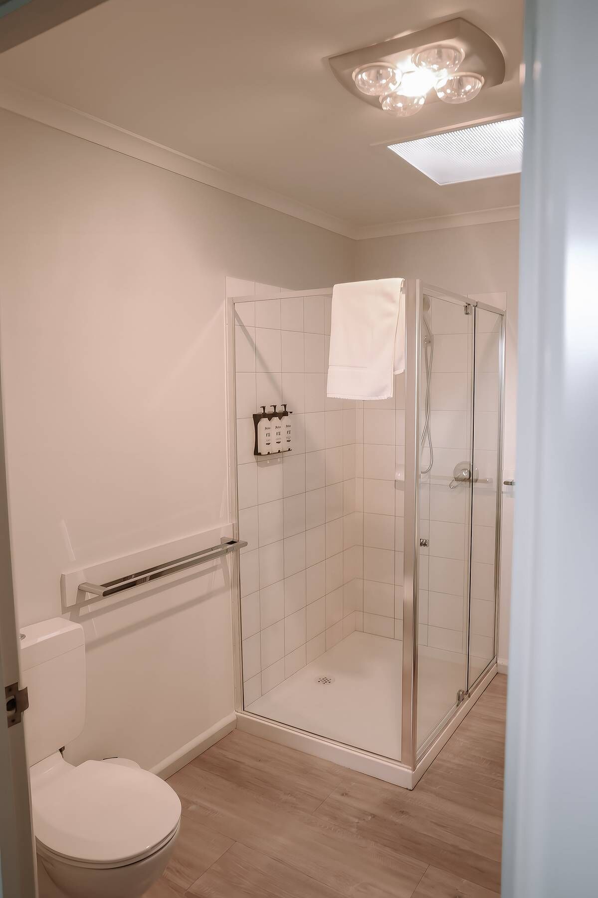 Een moderne badkamer met een glazen douchecabine, een toilet en een handdoekhouder.