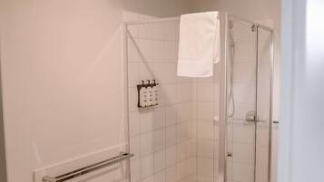 Een moderne badkamer met een glazen douchecabine, een toilet en een handdoekhouder.