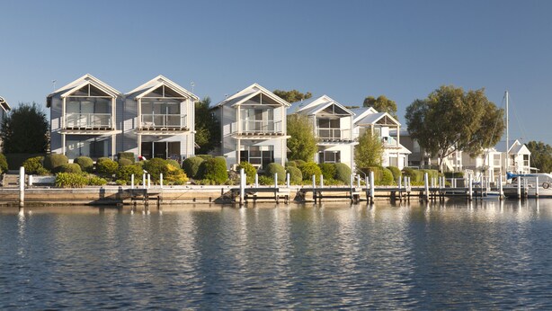 A waterfront property with multiple houses, each featuring balconies and large windows. - Captains Cove Waterfront Resort (Paynesville)