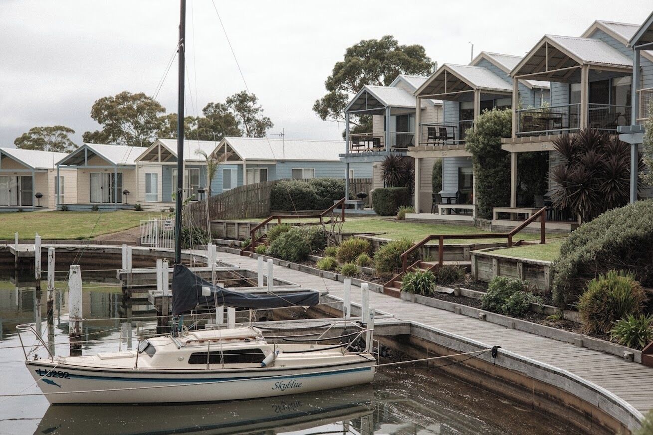 A row of waterfront mobile homes with a dock and a boat named 'Skyblue' moored in the water.
