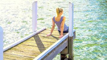 Iemand zit op een houten steiger die over het water uitsteekt.