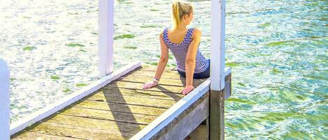 Una persona sentada en un muelle de madera que se extiende sobre el agua.