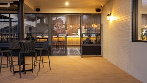 A restaurant with a bar area, wooden flooring, and a brick wall. - The Club Hotel (Gladstone)