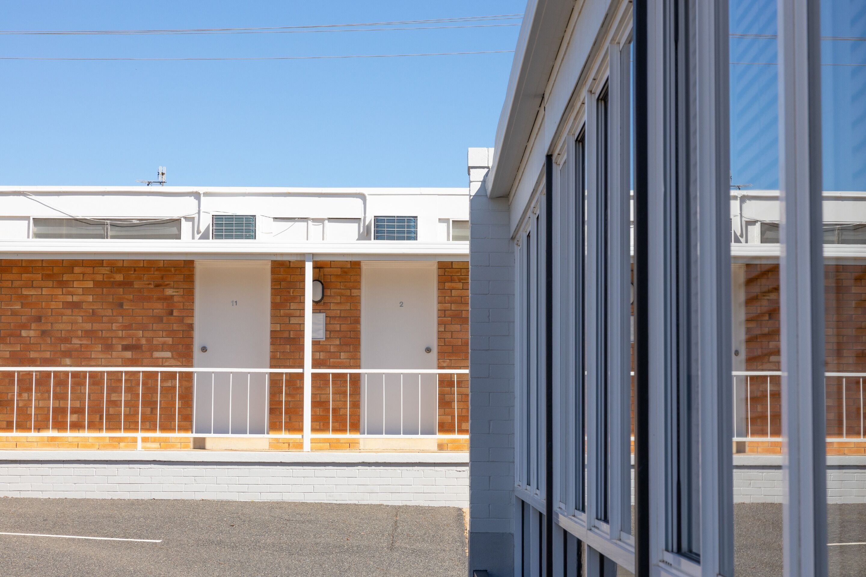 Un edificio con fachada de ladrillo, barandillas blancas y puertas numeradas.