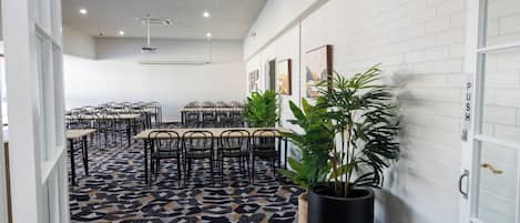 Una sala de reuniones moderna con suelo de patrón geométrico, paredes de ladrillo blanco y varias mesas y sillas.