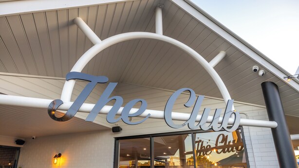 A restaurant entrance with a sign reading "The Club" and a visible outdoor seating area. - The Club Hotel (Gladstone)