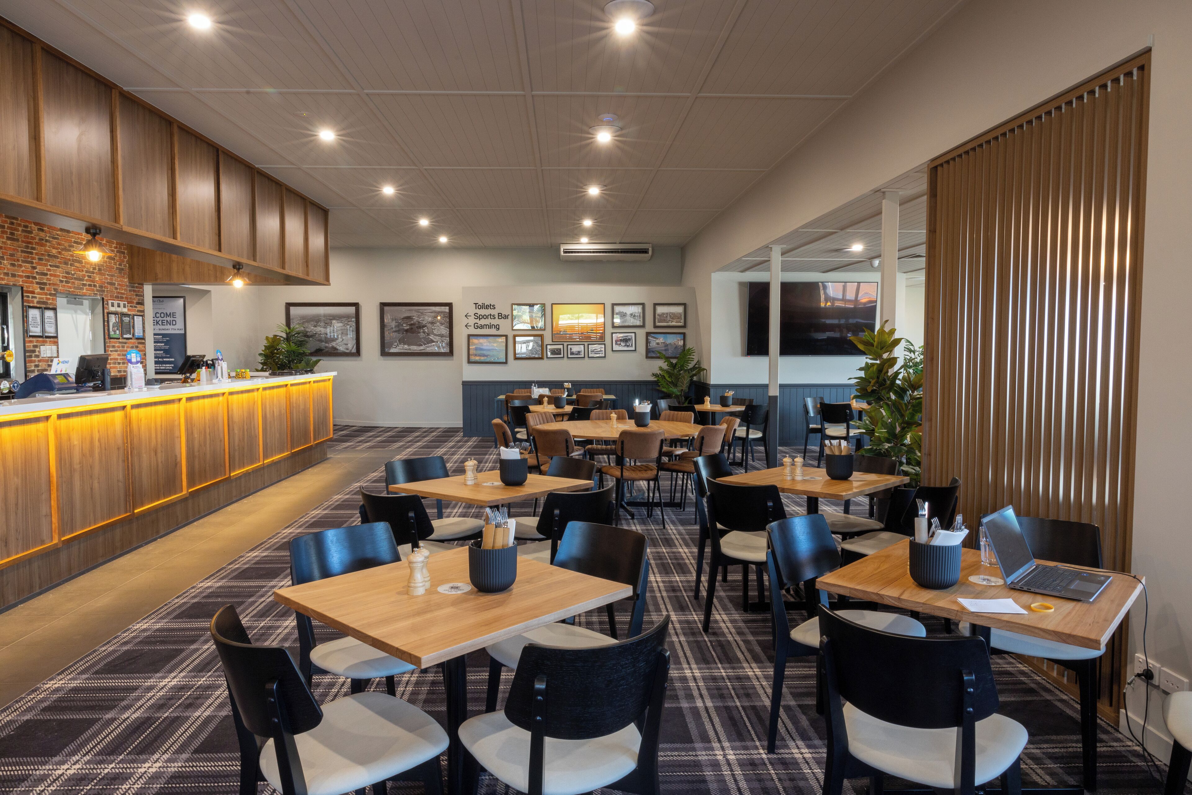 Un moderno vestíbulo de hotel con una recepción, varias zonas de estar y diversas comodidades, incluyendo un bar y una zona de juegos.