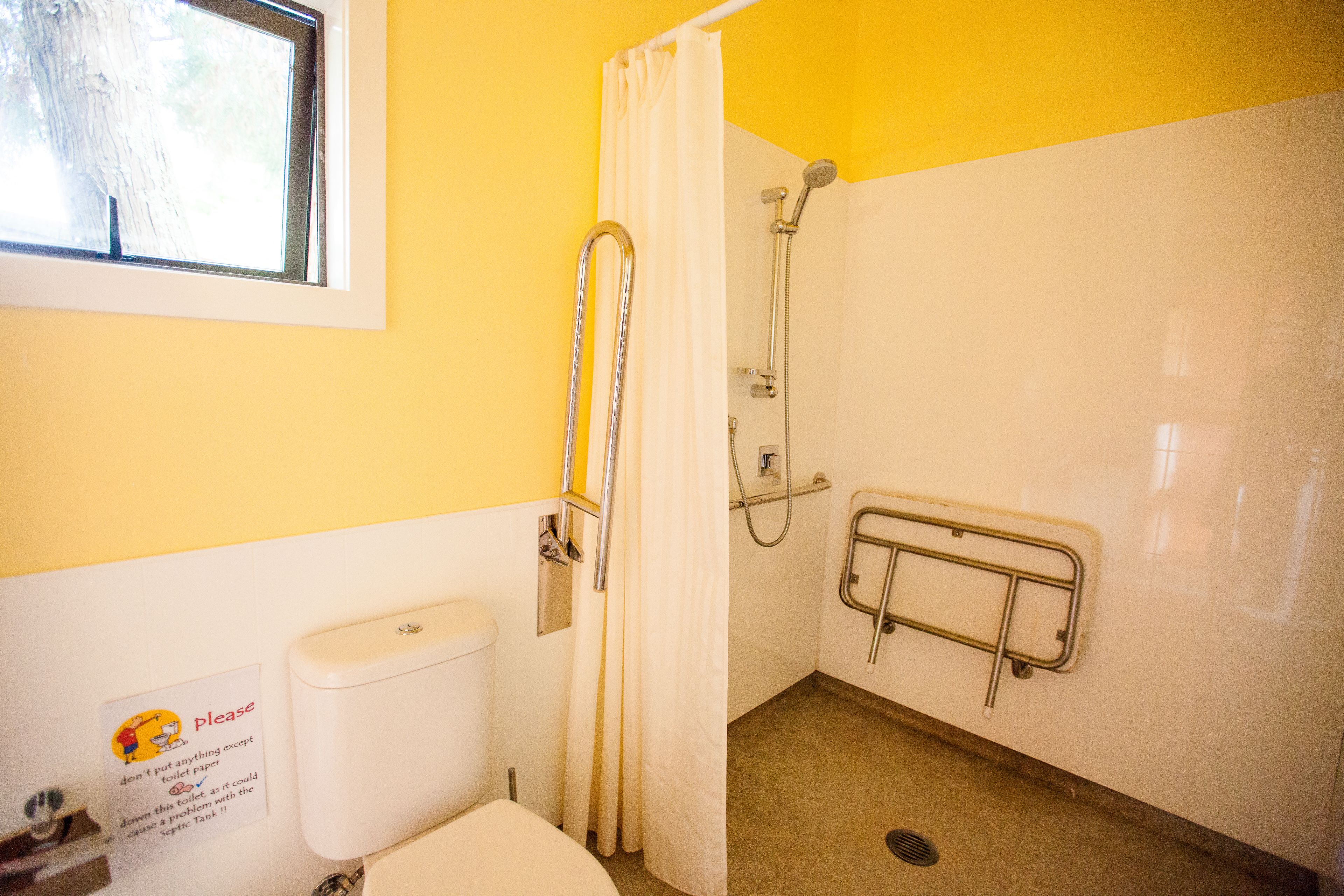 Een badkamer met toilet, douche en een handgreep.
