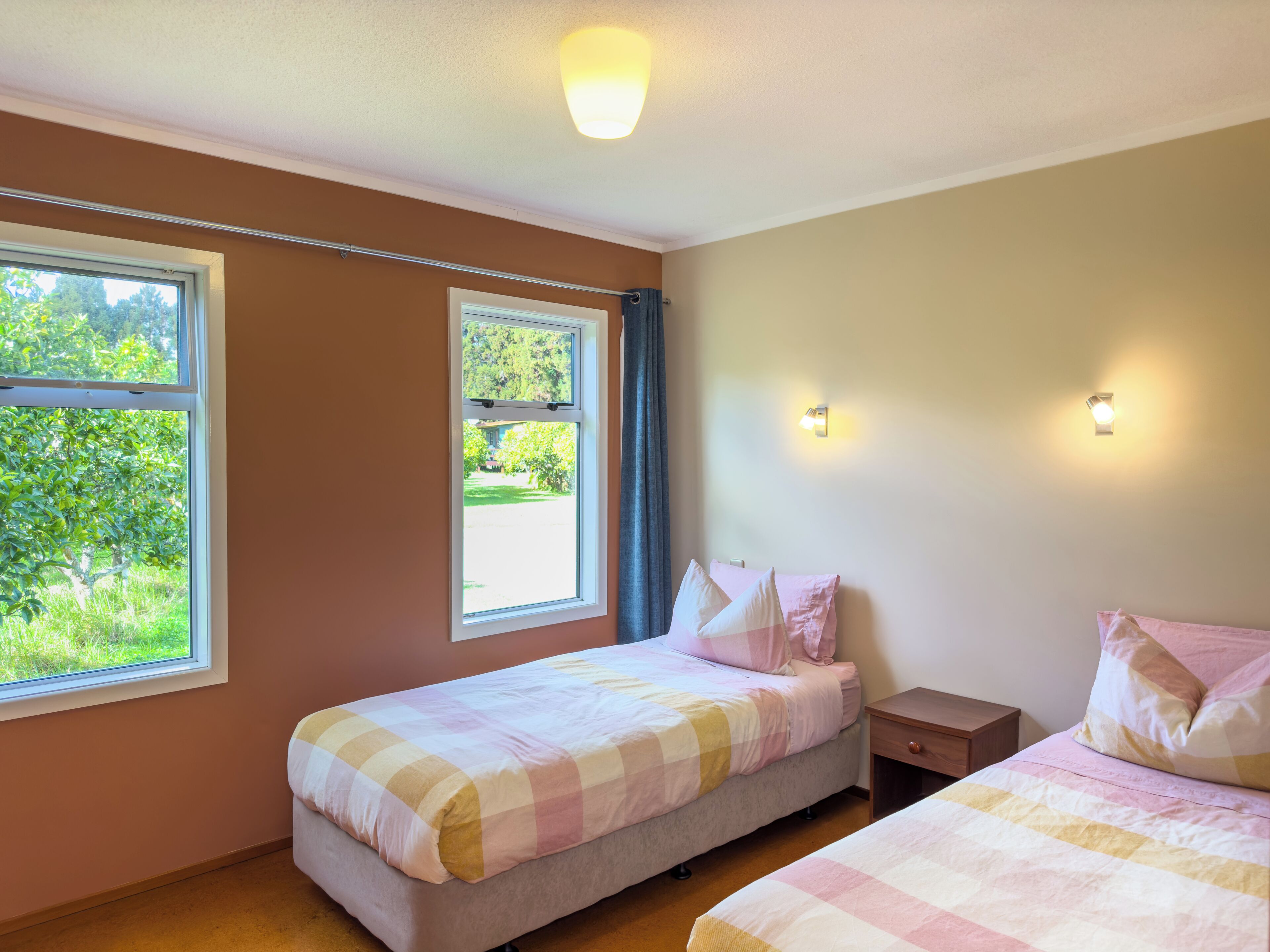 A bedroom with two beds, a window, and a nightstand.