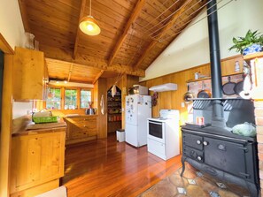 A wooden interior with a kitchen area featuring a stove, refrigerator, and wooden cabinets. - Relax a Lodge (Kerikeri)