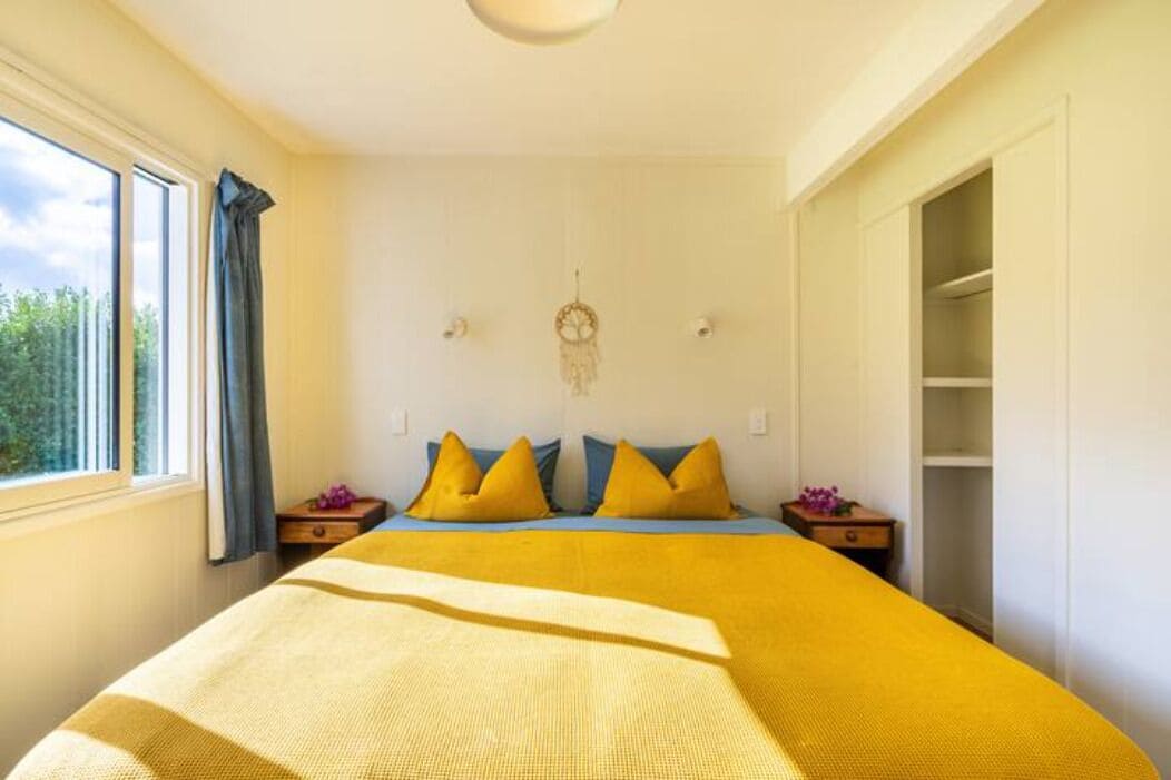 A bedroom with a bed, a window, a wardrobe, and a dreamcatcher on the wall.