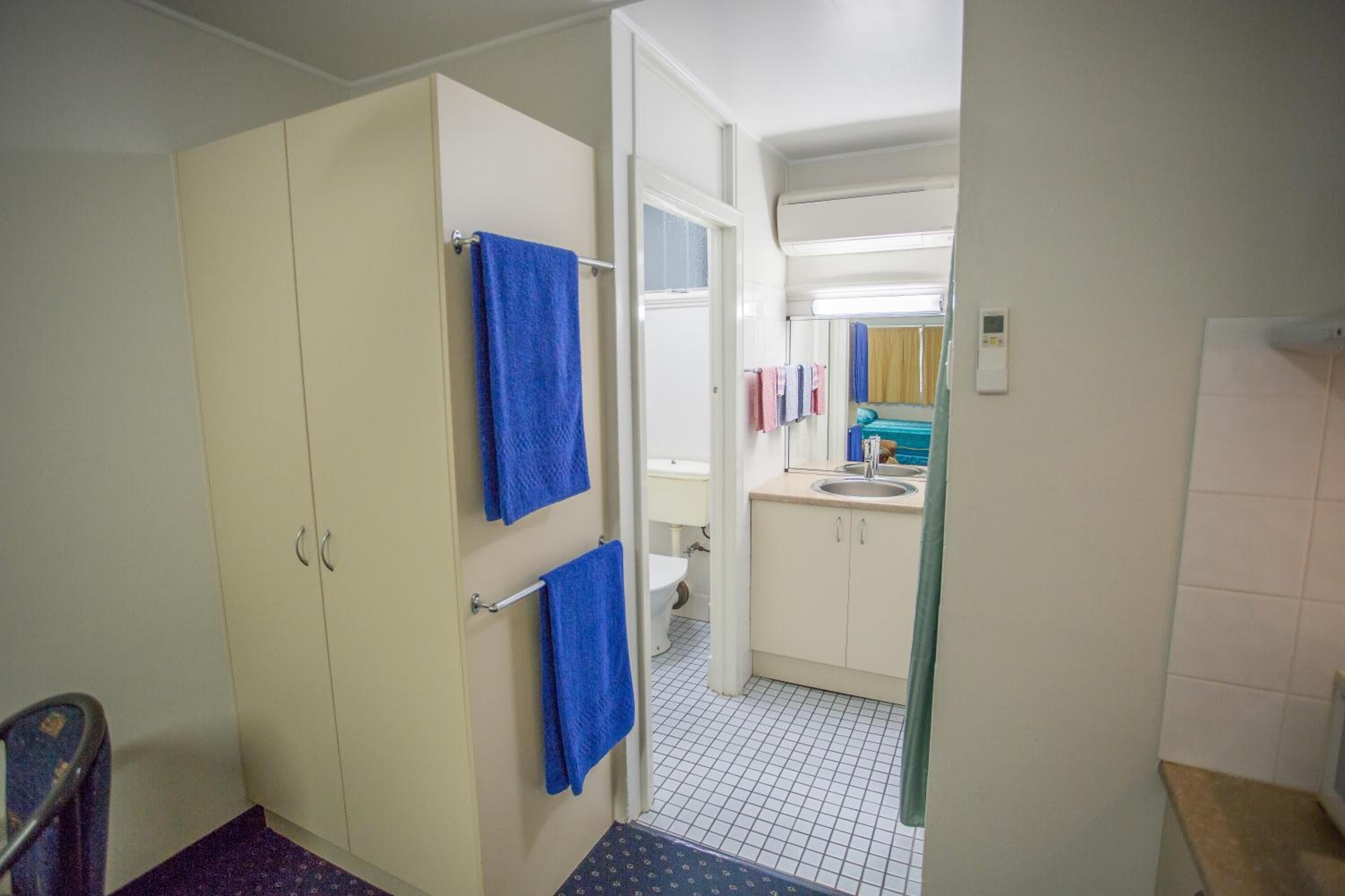A bathroom with a toilet, sink, and cabinets.