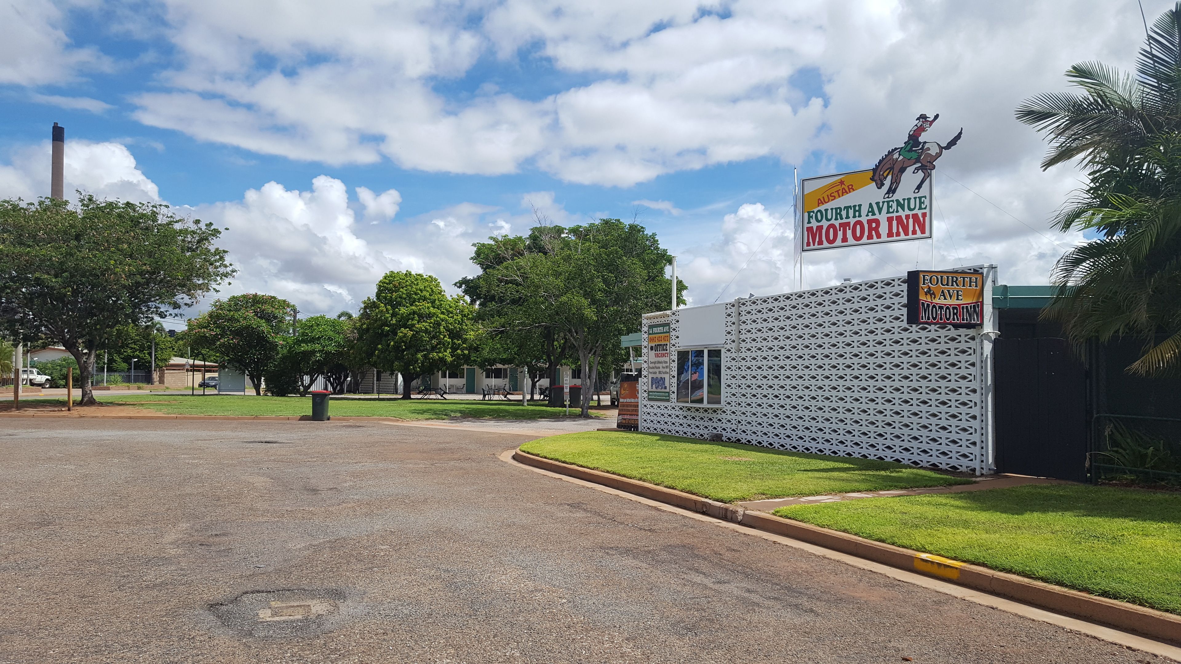 A parking lot with a building labeled "Fourth Avenue Motor Inn" and a signboard advertising a pool.