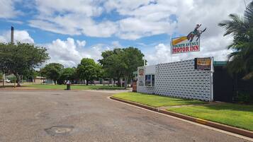 A parking lot with a building labeled "Fourth Avenue Motor Inn" and a signboard advertising a pool.