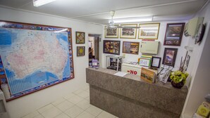 Un espace d’accueil comprenant une grande carte, des tableaux encadrés, un comptoir d’accueil et une chaise.