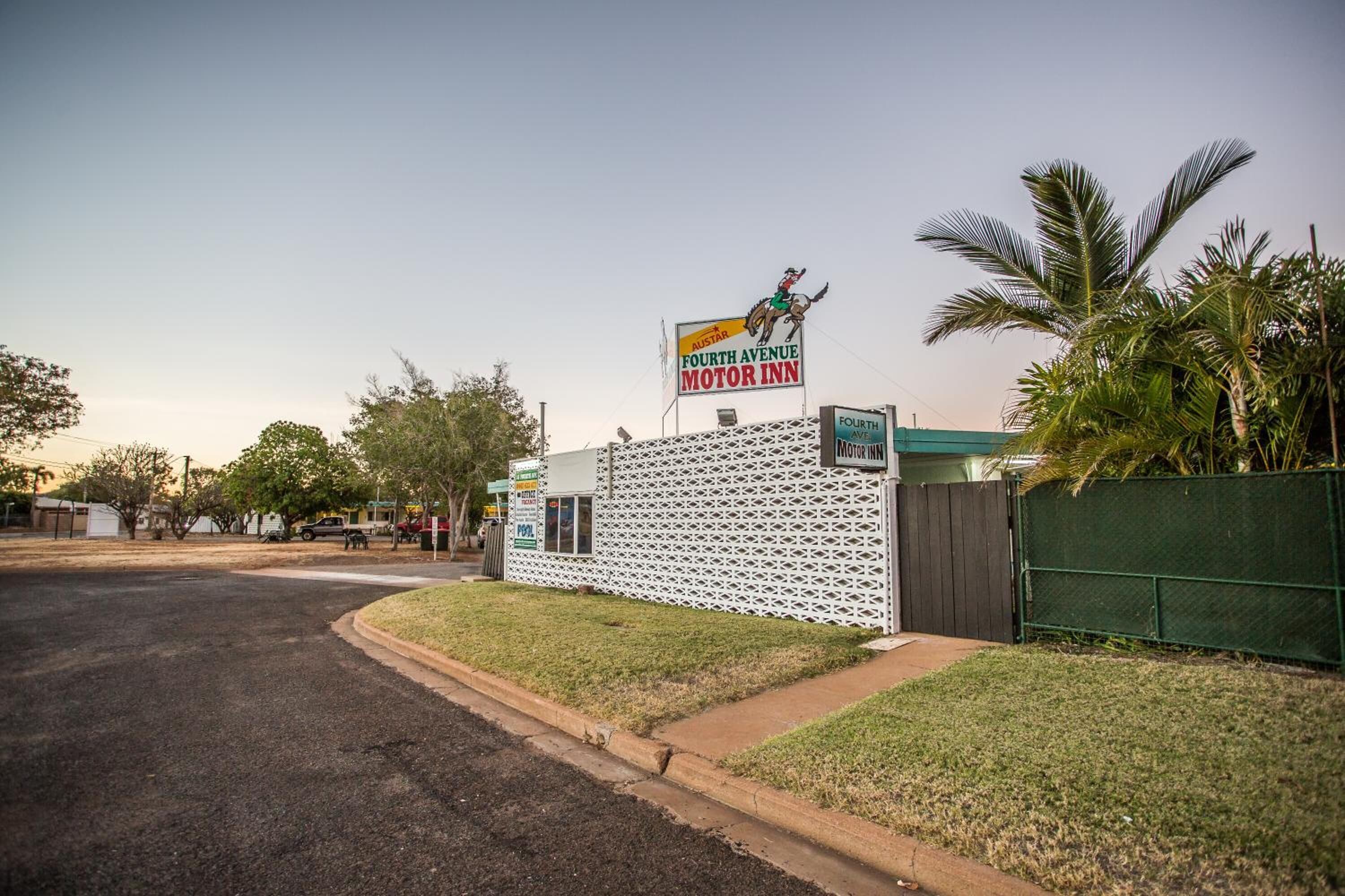 Un motel avec une enseigne indiquant « Fourth Avenue Motor Inn » et une mascotte sur le toit.