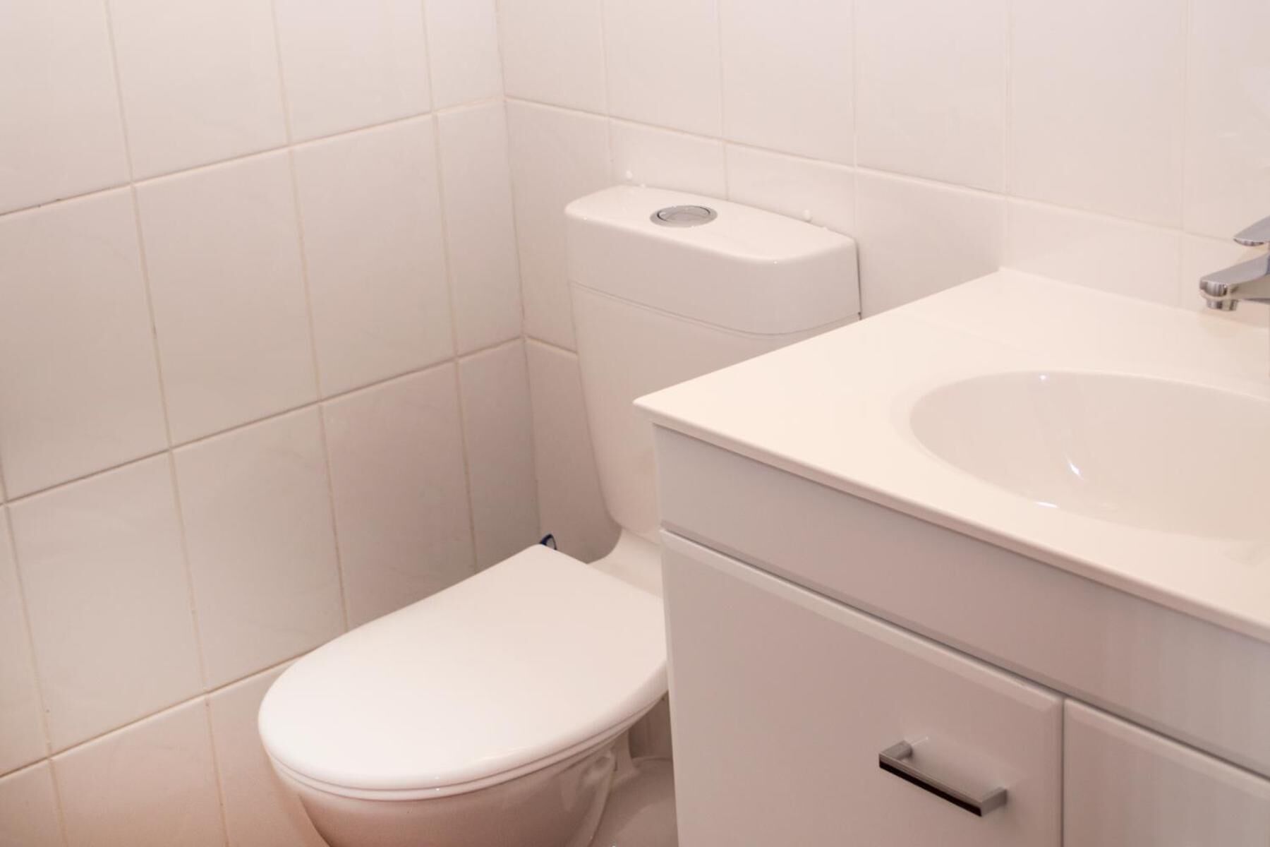 A small, white bathroom with a toilet, a sink, and a cabinet.