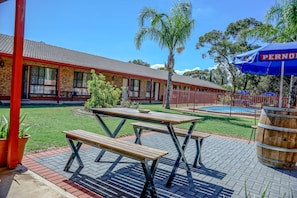 A brick building with a pool, picnic tables, and a palm tree. - Kadina Gateway Motor Inn (Kadina)
