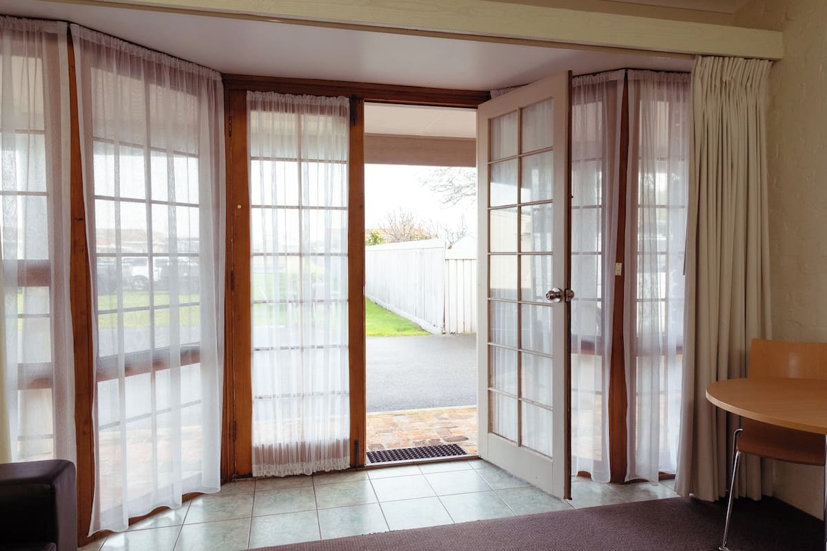 A room with a sliding glass door leading outside, a small table, and a chair.