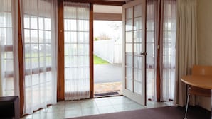 Una habitación con una puerta corrediza de vidrio que da al exterior, una mesita y una silla.