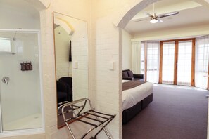 A bedroom with a bed, a shower, and a large window.