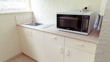 A kitchen with white cabinets, a sink, and a microwave.