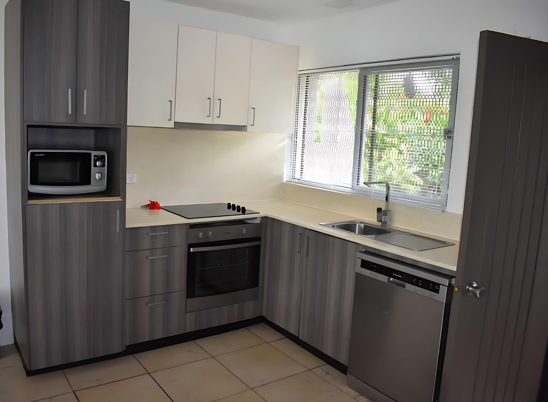 Una cocina compacta con gabinetes grises, un microondas, una estufa y un lavavajillas.