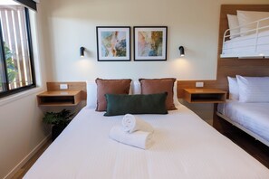 A hotel room with a large bed, two bedside tables, a window with blinds, and two wall-mounted light fixtures. - Currimundi Hotel Motel (Battery Hill)