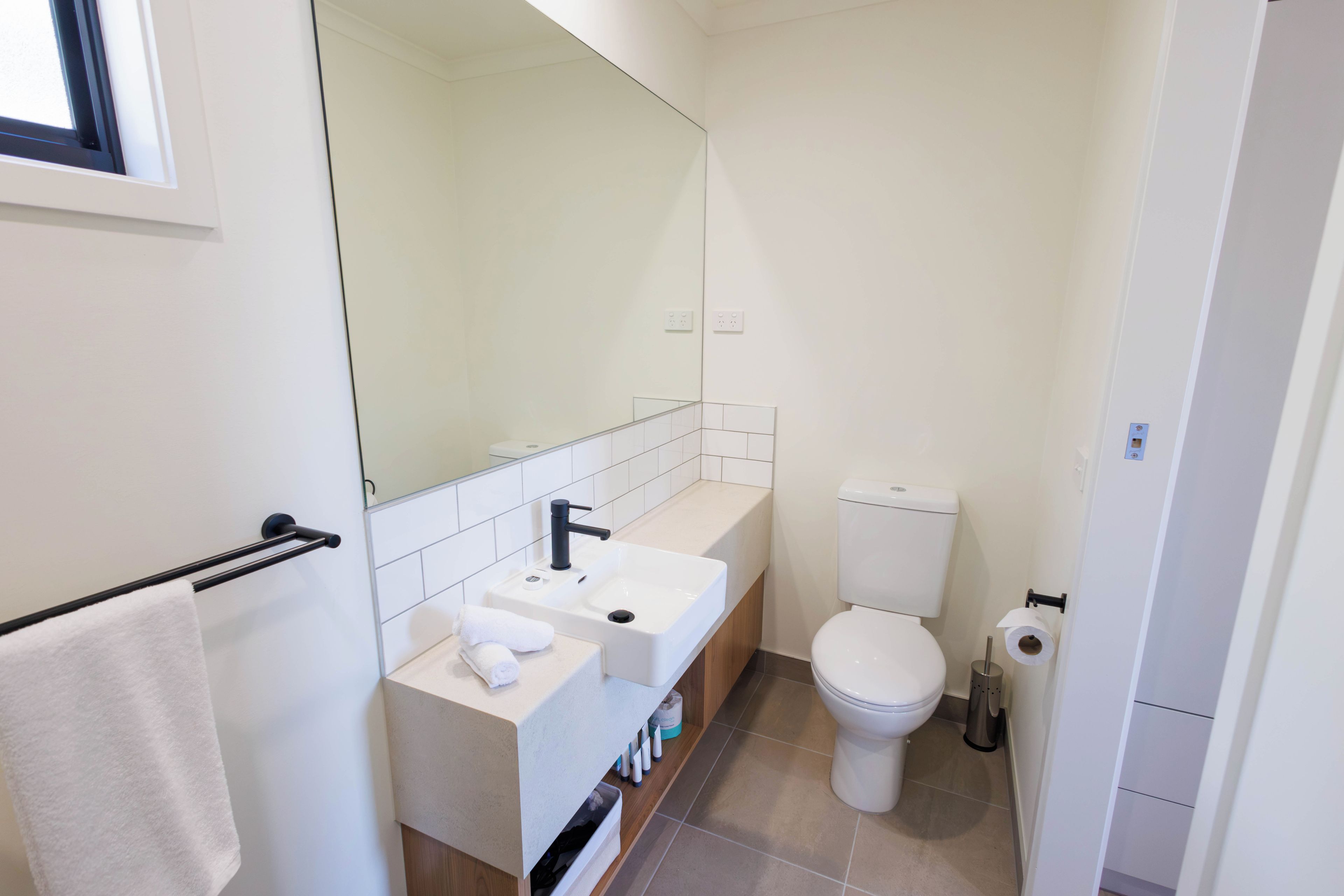 A modern bathroom with a white sink, mirror, and toilet.