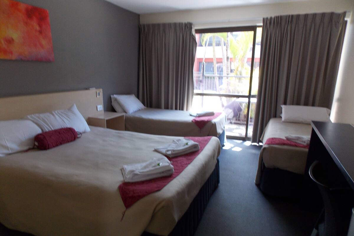Une chambre d’hôtel avec deux lits, un bureau et une vue sur l’extérieur.