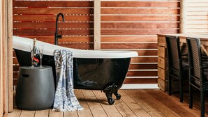 Ein Badezimmer mit einer freistehenden Badewanne, einem Handtuch und einer Champagnerflasche.