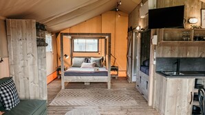 Ein gemütliches Zimmer mit Holzausstattung, einem Bett, einem kleinen Tisch, einer Couch und einer Küchenzeile.