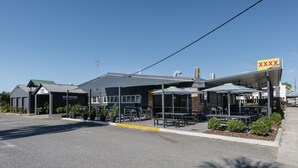 A building with outdoor seating and a covered area. - Boomerang Motor Hotel (West Mackay)
