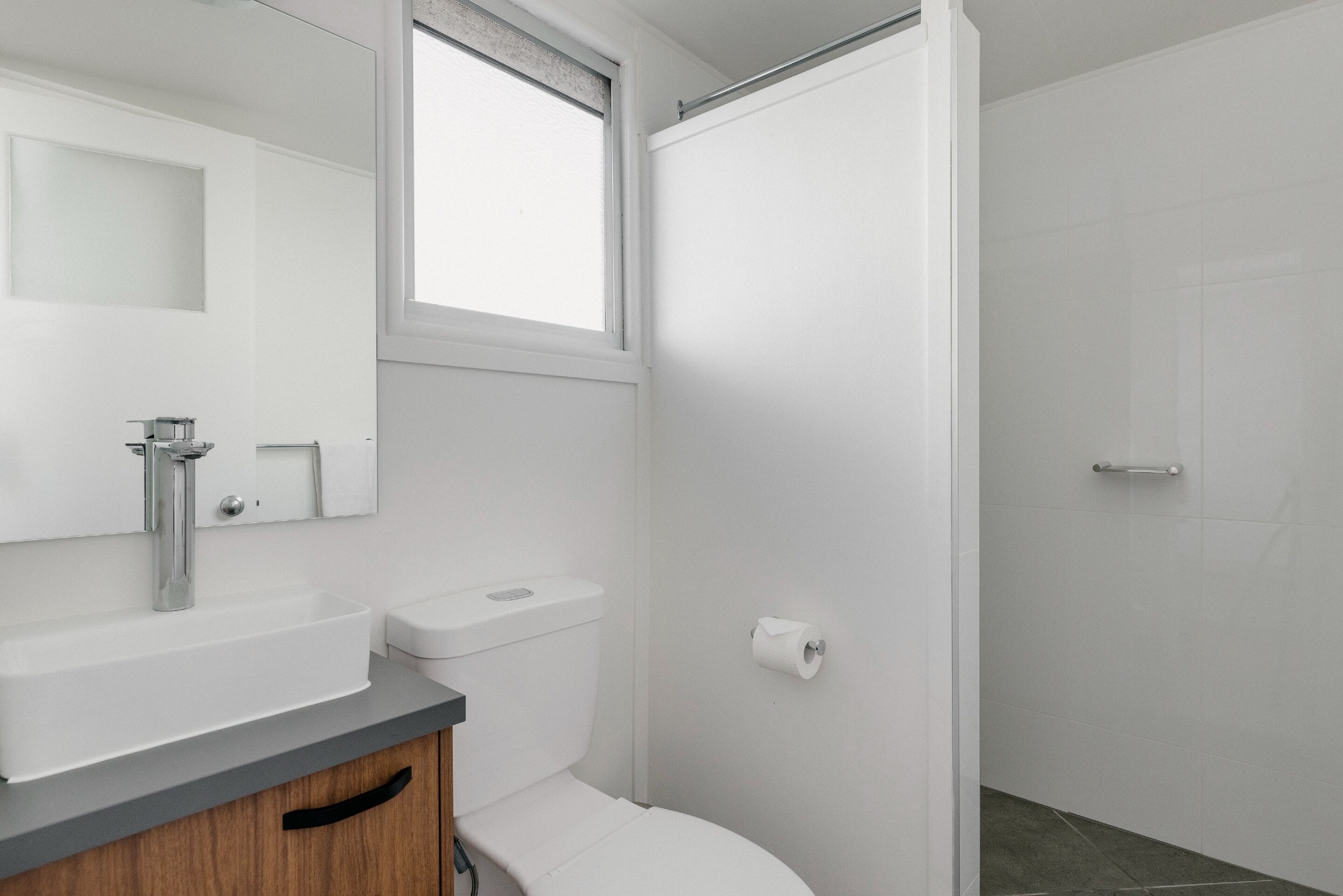 A modern bathroom with a white sink, toilet, and shower.
