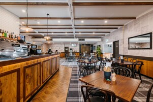 Un restaurante con barra de madera, varias mesas y sillas.