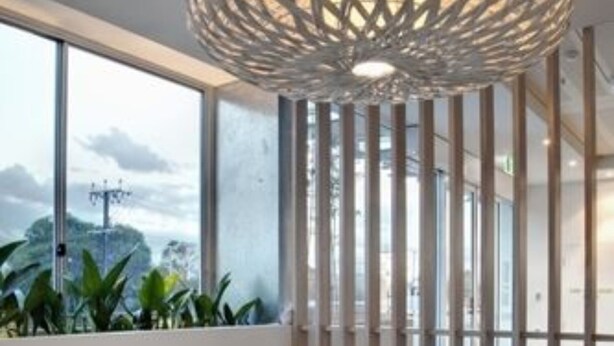 A modern interior with a white table and green cushioned benches, a decorative woven light fixture, and a view through large windows. - Walkers Arms Hotel (Walkerville)