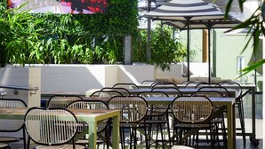 An outdoor seating area with tables and chairs, a large screen displaying a sports event, and lush greenery. - Walkers Arms Hotel (Walkerville)