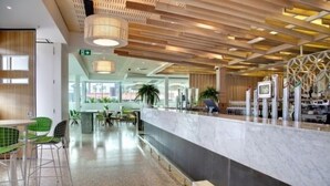A modern hotel lobby with a marble reception desk, green chairs, and a wooden ceiling design. - Walkers Arms Hotel (Walkerville)