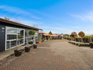 A modern building with large windows, a paved driveway, and various potted plants. - Dunrovin Motel (Taupo)