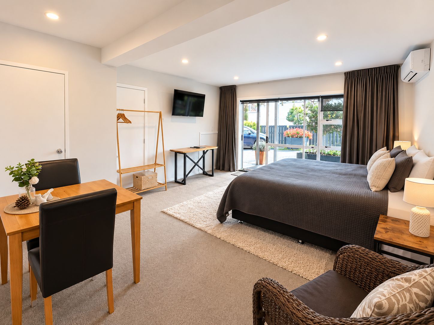 Un dormitorio moderno con cama, televisor, escritorio y silla.