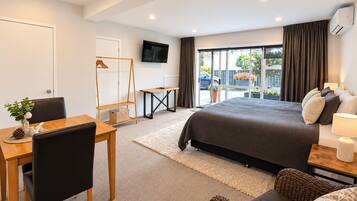 Un dormitorio moderno con cama, televisor, escritorio y silla.
