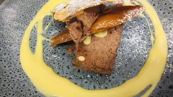 Un postre en un plato moteado con un hilo de salsa amarilla.