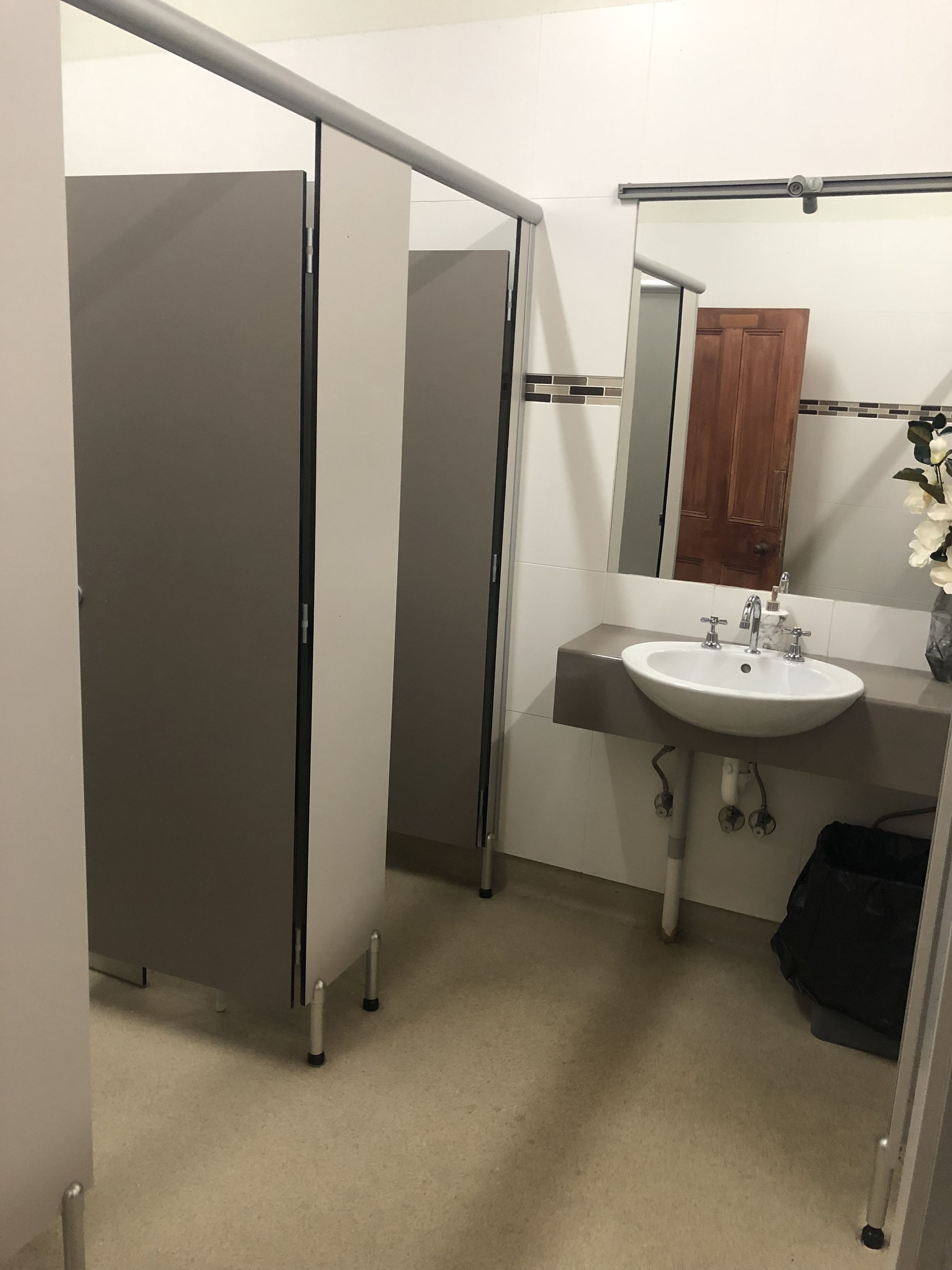 A bathroom with a white sink, a mirror, and a wooden door.