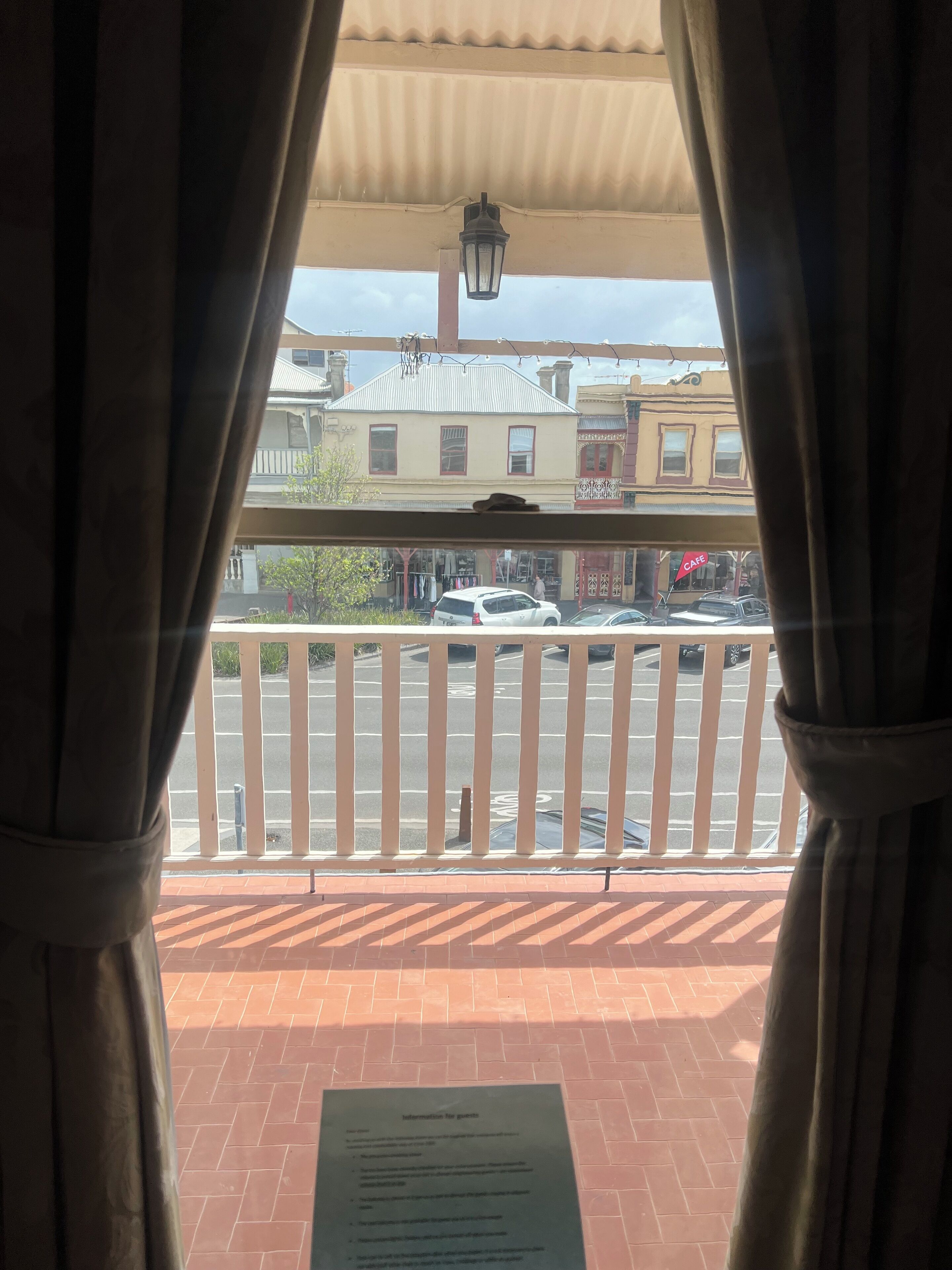 A balcony with a view of a street, a signboard, and a lamp post.