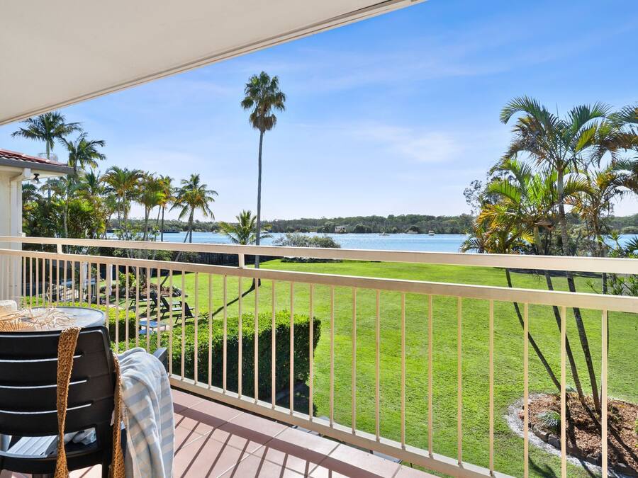 A balcony with a view of a lake and palm trees.
