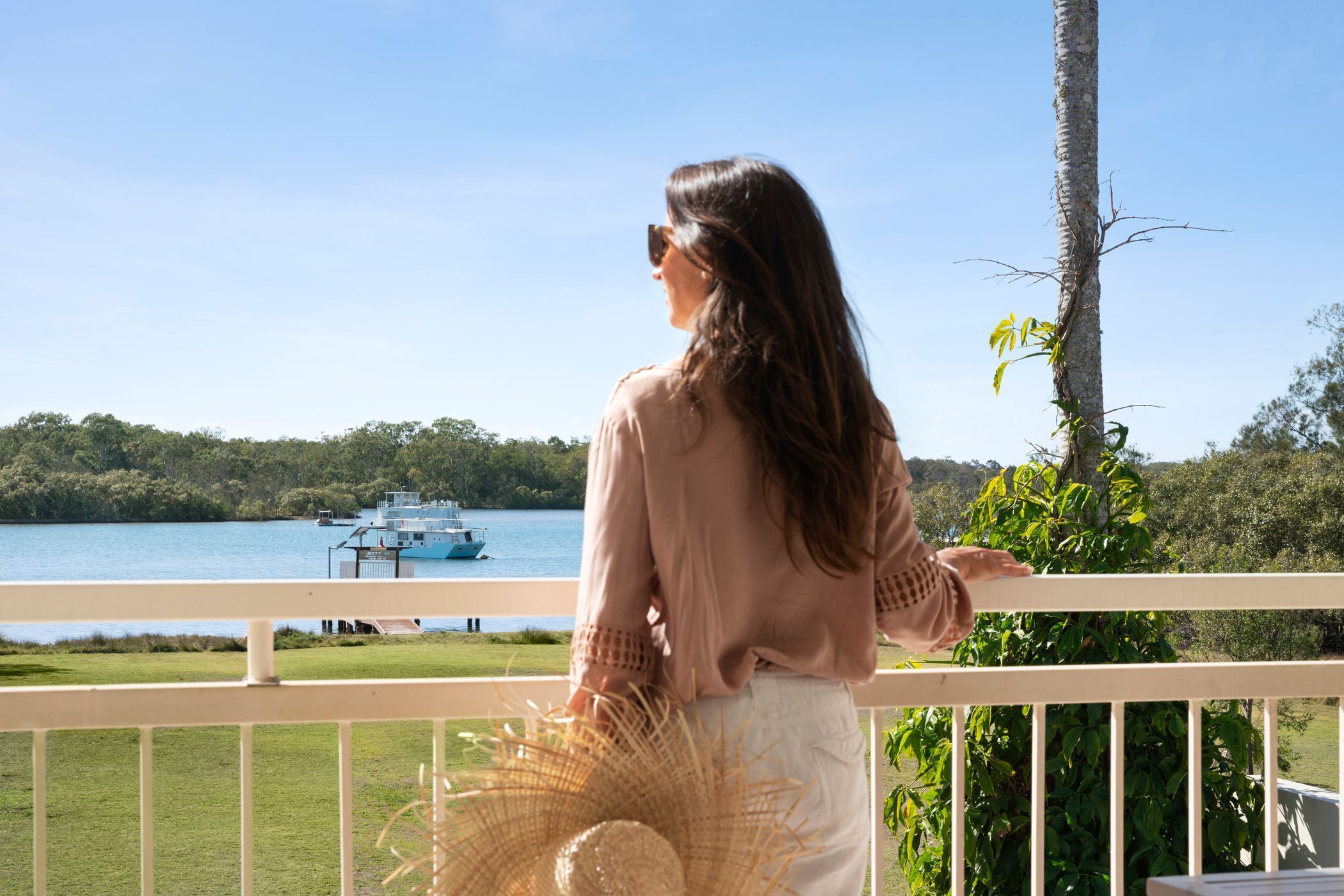 A person standing on a balcony overlooking a lake with a boat in the distance.