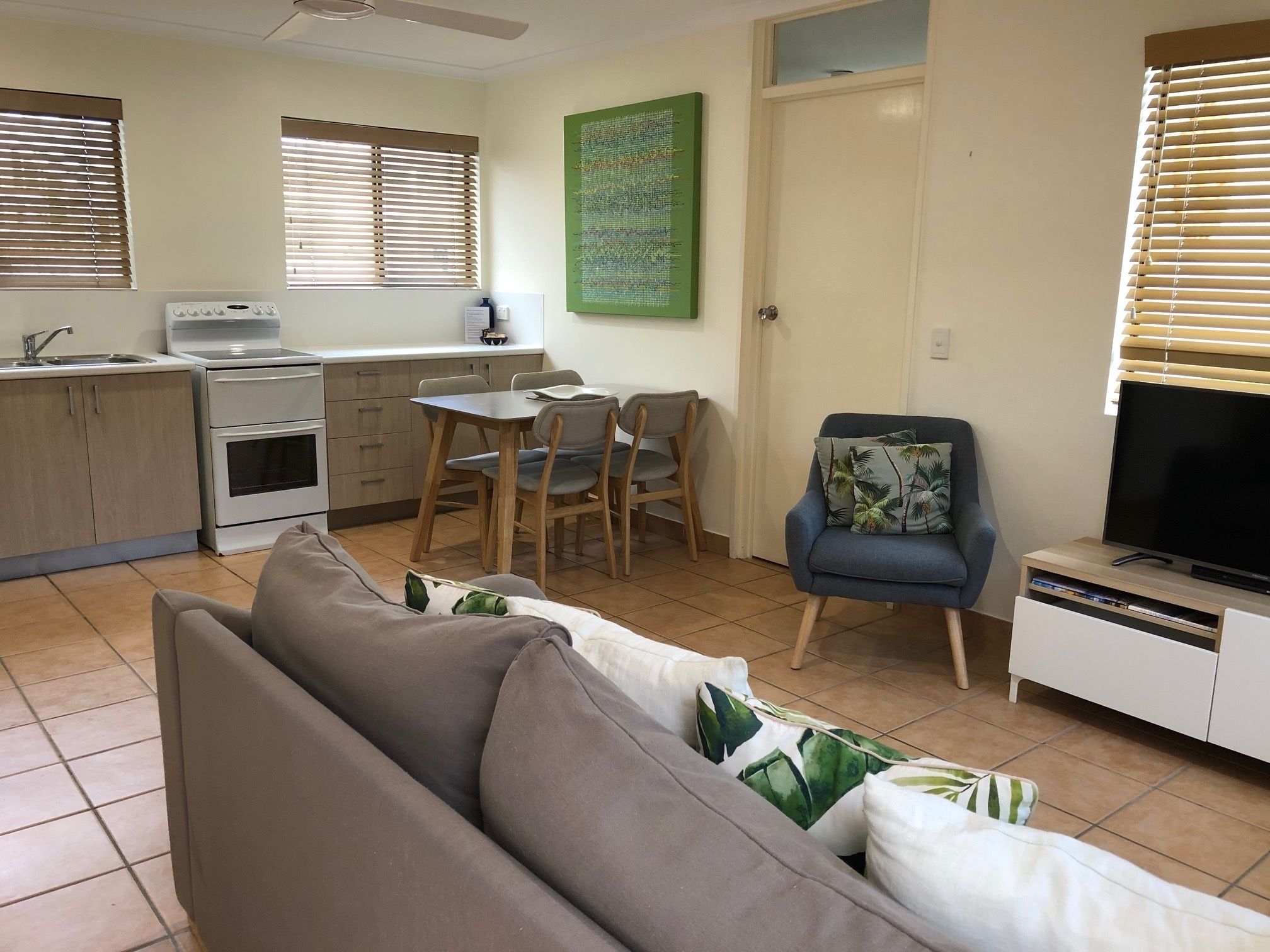Un espacio habitable compacto con kitchenette, comedor, sofá y televisor.