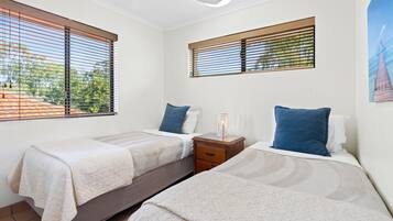 A bedroom with two beds, each with a pillow and a bedside table.